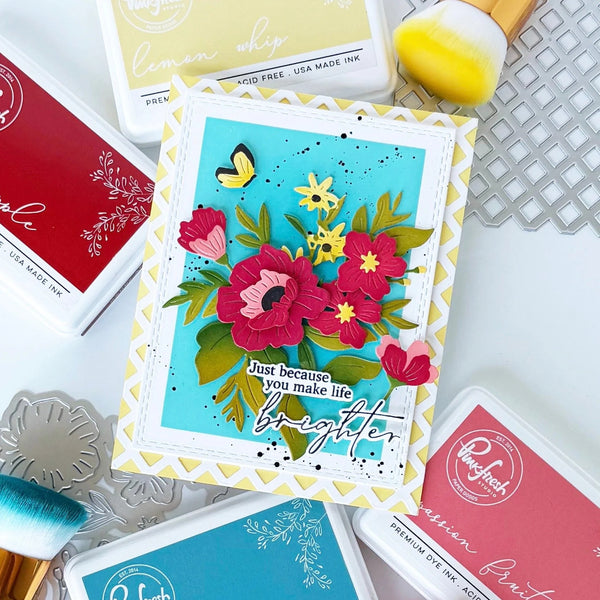 Colorful floral card with 'Just because you make life brighter' text, surrounded by craft supplies on a white surface.