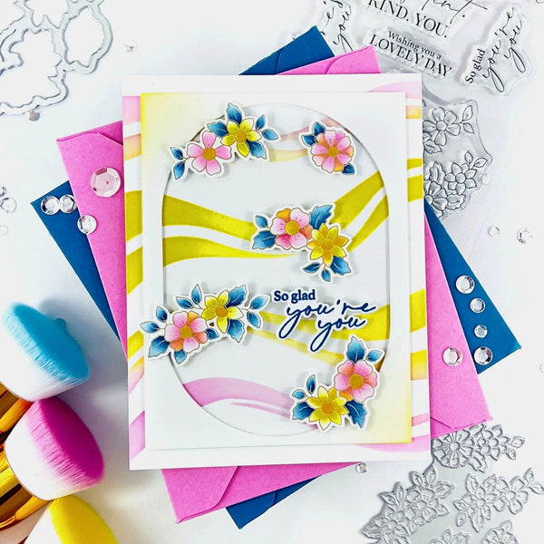 Colorful card with floral design and text, surrounded by crafting tools on a white background