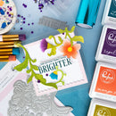 Card with floral design and text, surrounded by stamping tools on a blue background
