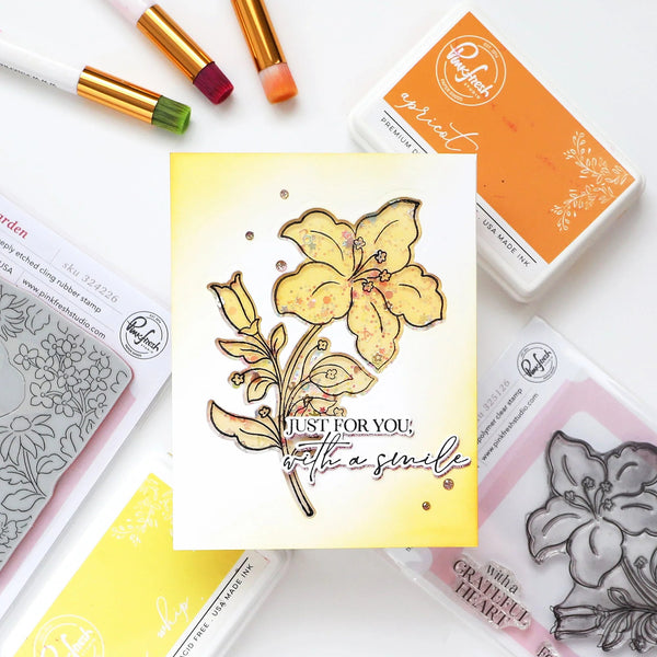 Card with floral design and text, surrounded by rubber stamps and ink pads on a white background