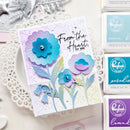 Card with blue and purple flowers and 'From the Heart, for you' text, surrounded by craft supplies.
