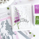 Handmade card with floral design and 'Happy Birthday' text, surrounded by stamping tools and ink pads.