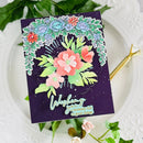 Decorative birthday card with floral design and text on a white surface with green leaves.