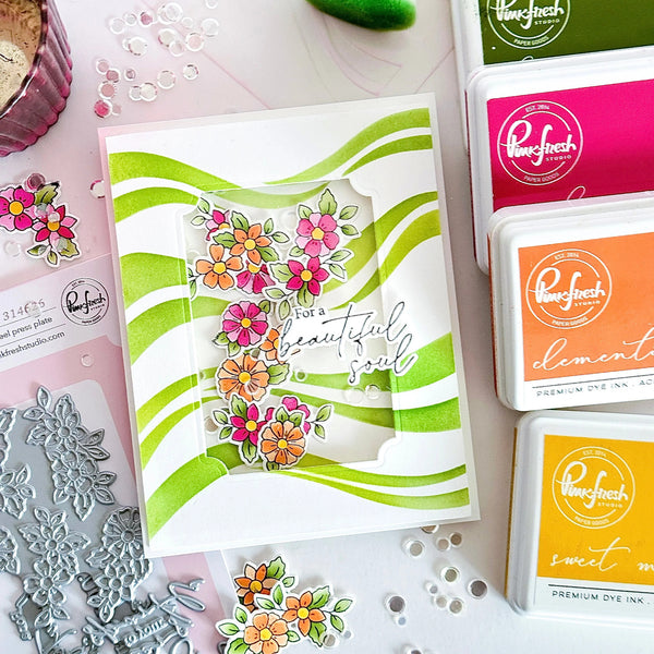 Card with floral design and text, surrounded by stamping supplies on a white surface