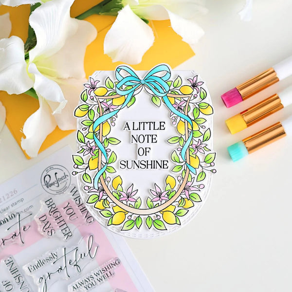 Decorative clear stamp with floral design and text 'A Little Note of Sunshine' on a white background with flowers and markers.