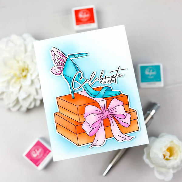 Greeting card with a blue high heel shoe and gift box design, surrounded by flowers and stamps.