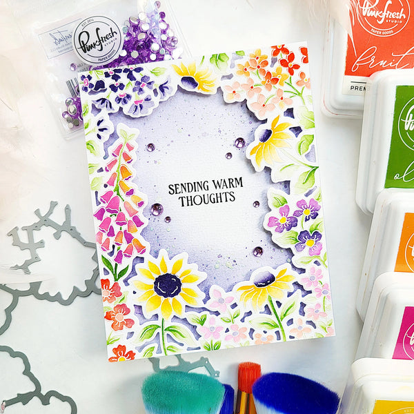 Colorful card with floral design and 'Sending Warm Thoughts' text, surrounded by craft supplies.