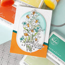 Clear stamp with floral design and 'Just a little sunshine for today' text on an orange card with stamp pads in the background.