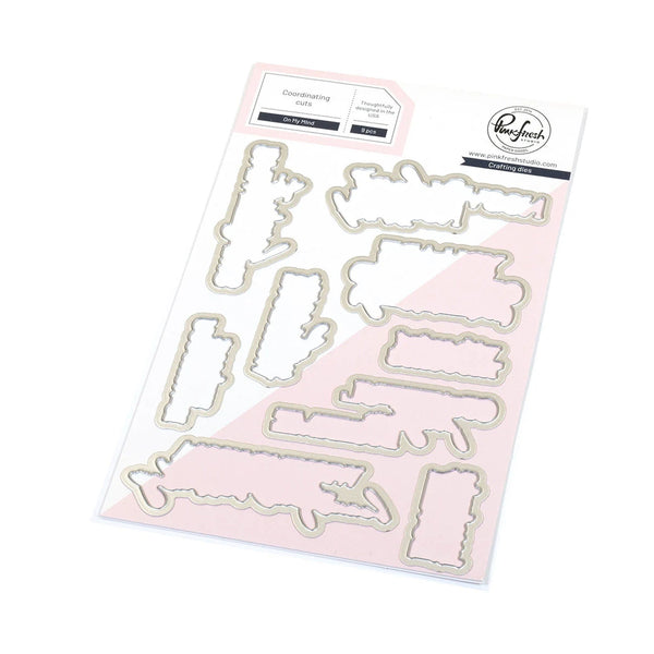 Set of metal dies on a pink cardstock with brand logo.