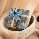 Gift box with blue ribbon and decorative paper inside a woven basket