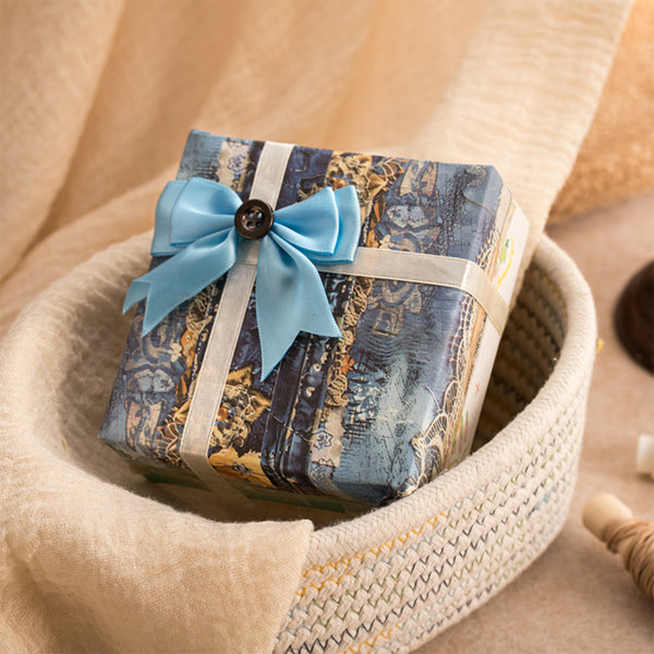 Gift box with blue ribbon and decorative paper inside a woven basket