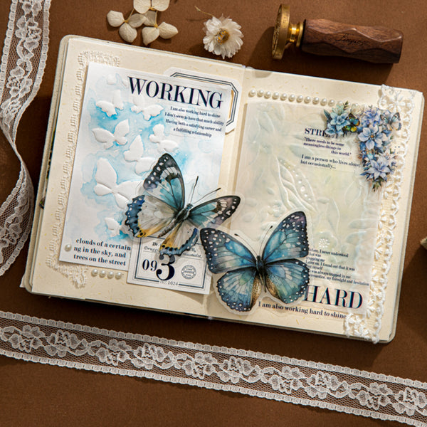 Open book with decorative elements including butterflies and lace on a brown surface.