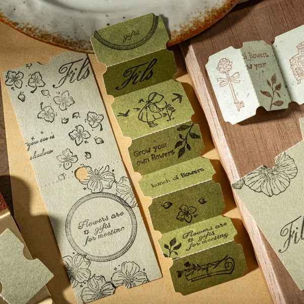Set of decorative paper tags with floral designs and text on a wooden surface.