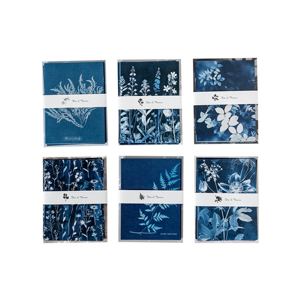 Set of blue and white botanical notebooks with visible branding on a white background