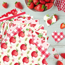 Collection of strawberry-themed paper products on a wooden surface with strawberries around.
