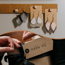 Leather teardrop earrings on a cork board with 'open me' brand tag.