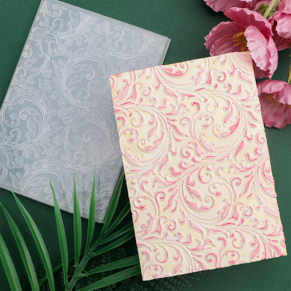 Two patterned notebooks, one gray and one pink with floral design, on a green surface with flowers and leaves.
