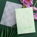 Two notebooks with circular patterns on a green background with flowers and leaves.