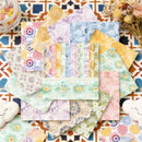 Collection of colorful patterned paper sheets on a decorative surface with flowers and a jar.