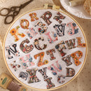 Embroidery hoop with floral alphabet letters on a beige background