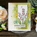 Greeting card with floral design and 'Congratulations' text on a wooden surface with flowers.