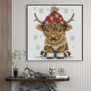 Framed cross-stitch art of a reindeer with a red hat on a wall above a console table.