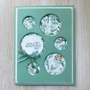 Decorative card with floral designs and a central message on a wooden surface