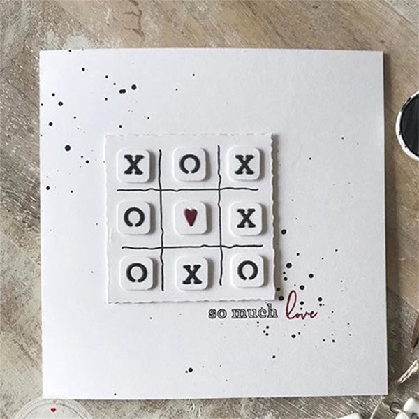 Card with tic-tac-toe design featuring 'XO' and 'O' symbols, with a heart in the center, on a textured surface.