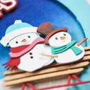 Two snowman cookies with decorative hats and scarves on a blue plate.