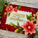 Decorative card with red and green floral elements and 'warm wishes' text on a wooden surface.