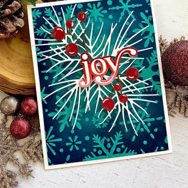 Christmas card with 'joy' text surrounded by holly leaves and berries on a blue background.
