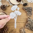 White floral die cut on a wooden surface with natural elements