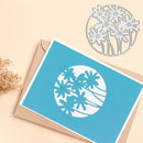 Blue card with floral cutout design on a beige background
