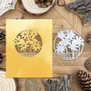 Metallic gold and silver floral cutouts on a wooden surface with natural elements.