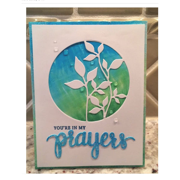 Card with blue and green design and 'You're in my prayers' text on a marble surface