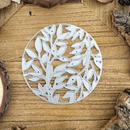 Circular metal cutting die with leaf pattern on a wooden surface