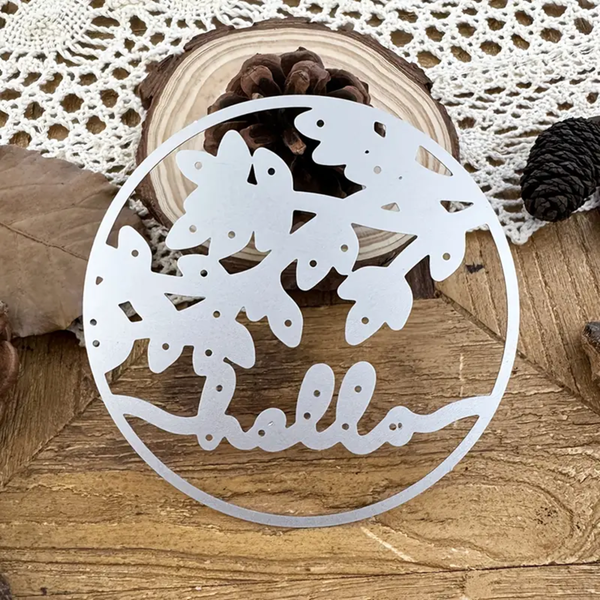 Decorative white metal cutout with butterfly design and 'hello' text on a wooden surface.