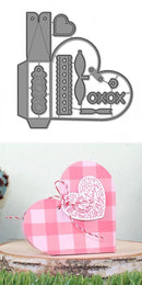 Metal die set with decorative elements and a heart-shaped pink box on a light background