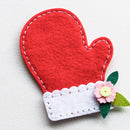 Red heart-shaped felt item with white trim and a pink flower on a light gray background