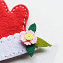Red heart-shaped fabric with a pink flower and green leaves on a white background