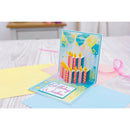 Pop-up birthday card with candles and balloons on a bed