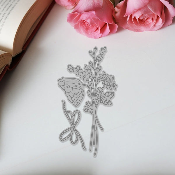 Metal floral cutting dies on a white surface with pink roses and an open book in the background.