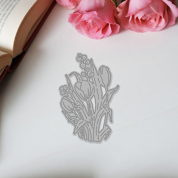 Metal floral bookmark on a white surface with pink roses and an open book in the background.