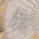 Metallic letter stamps on a lace doily with wooden surface underneath