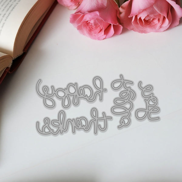 Decorative metal word cutout on a white surface with pink roses and an open book.