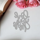 Decorative metal word cutout on a white surface with pink roses and an open book.