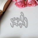 Decorative word cutout spelling 'lovelies' on a white surface with pink roses and an open book.