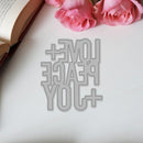 Metallic cutout with 'I love peace you' text on a white surface with pink roses.