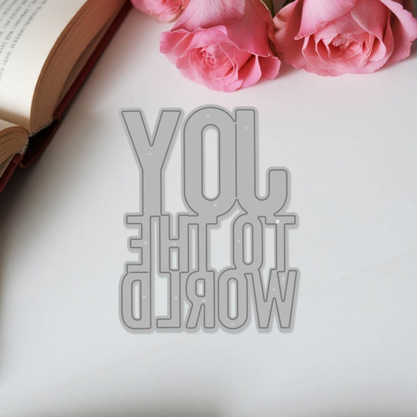 Metallic 'You are the world' cutout on a white surface with pink roses and an open book.