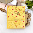 Yellow card with butterfly and heart designs on a decorative surface